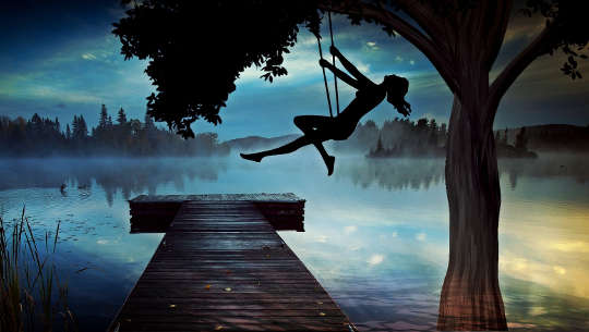 silhouette of a girl high on a swing at dusk over looking a foggy lake