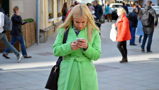 Does The Internet Really Make You Smarter? woman on the street looking intently at her phone
