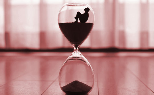 Time, Choice, and Clock Time Addiction Human sitting on the sand in the top section of an hourglass