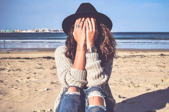 How to Heal the Spiritual Wound from Childhood Trauma or Abuse young woman sitting on a beach with her face hidden in her bands