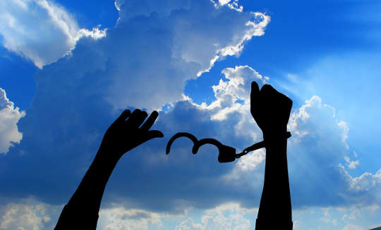 Releasing Feelings that Cramp Your DNA arms up in the air with one hand freed from handcuffs