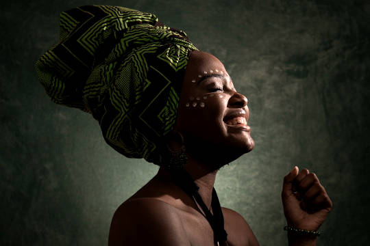 Four Requirements for Living in Joy African woman wearing a headress with eyes closed and smile