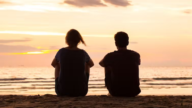 two people sitting by the ocean
