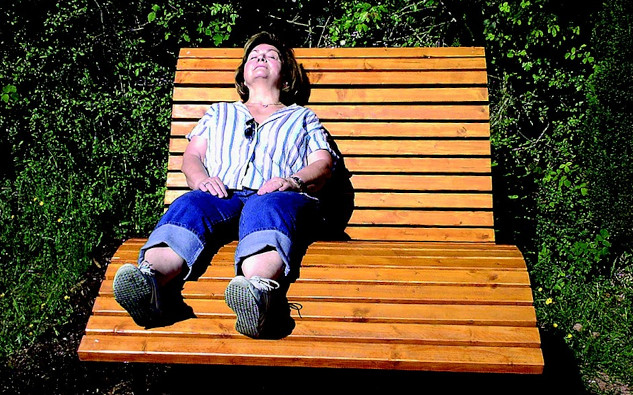 a woman relaxing on a bench with the sun shining on her