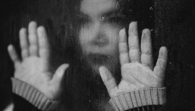 a blurred image of a woman with her hands flat out on a window. Image by Kleiton Santos from Pixabay.