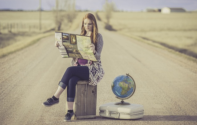 The Joy of Discovery: Seeking Purpose in the Unknown A woman sitting on a stool on a road with a world globe next to her.