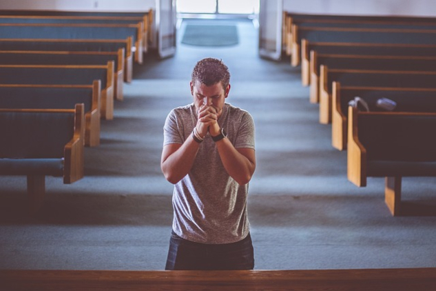 A man kneeling in a church praying. Image by Pexels from Pixabay.&nbsp;Is God Bipolar? 