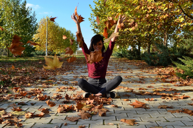 Woman sitting outside with arms up in a gesture of happiness and success.&nbsp;