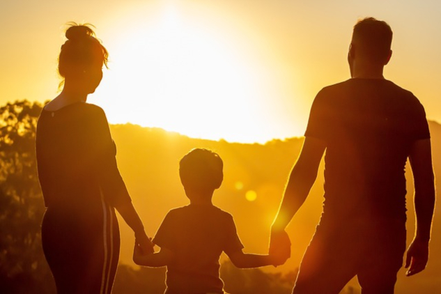 A family standing holding hands in front of the rising sun.&nbsp;Image by s05prodpresidente from Pixabay.