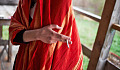 person in red shawl holds cigarette