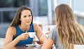 two women facing each other having coffee