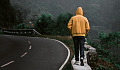 a man on a solitary walk on a path next to a paved road